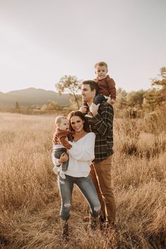 a man and woman are holding their son in the middle of a field with tall grass