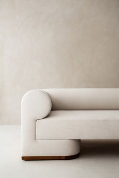 a white couch sitting on top of a floor next to a wall