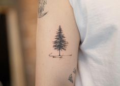 a person with a tattoo on their arm and a pine tree in the middle of his arm