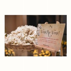 a basket filled with white flowers next to a sign that says, veri re veri