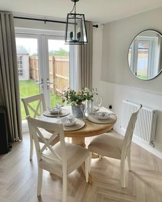 a dining room table with four chairs and plates on it, in front of a sliding glass door