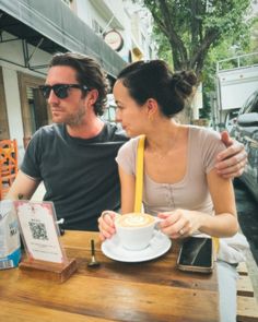 a man and woman sitting at a table with a cup of coffee