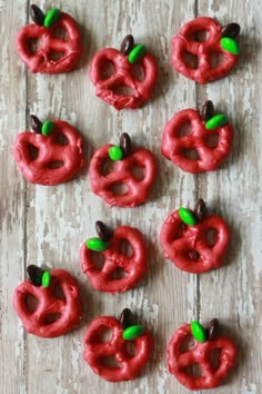 red pretzels are arranged in the shape of apples on a white wooden surface