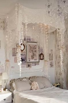 a white bedroom with chandelier, bed and pictures on the wall above it