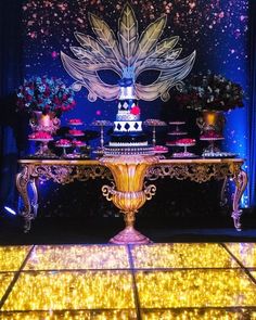 a table topped with a cake covered in frosting next to a wall filled with lights