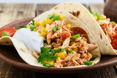 two tacos on a plate with corn and tomatoes