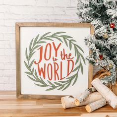 a christmas tree next to a sign that says joy in the world and some rolled up logs