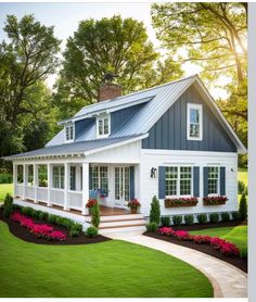 a white house with blue trim and windows on the front porch is surrounded by flowers