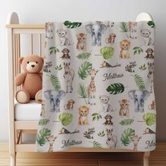 a teddy bear sitting next to a baby crib with personalized blankets on it