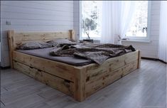 a bed sitting in the middle of a room next to a window with white curtains