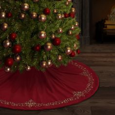 a christmas tree with red and gold baubles on the top, in front of a fireplace