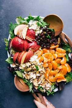 a wooden bowl filled with fruit and nuts