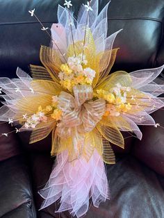 a yellow and white flower arrangement sitting on top of a black couch