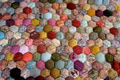 a multicolored knitted pillow with hearts on it's back and sides