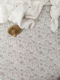 an unmade bed with white sheets and pillows on top of it, next to a wooden button