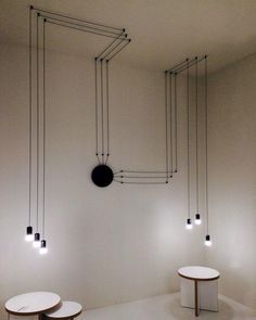 three round tables are in the middle of a room with black and white lights hanging from the ceiling