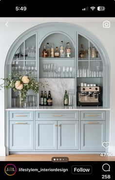 a blue bar with lots of bottles and glasses on top of the shelves in front of it