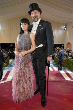 a man in a tuxedo standing next to a woman on a red carpet