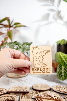 a person holding up a wooden sticker that says explore minnesota