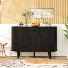 a black cabinet with a bowl of fruit on top of it next to a potted plant