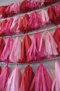 red and pink tissue tassels hanging on a wall