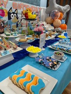 a blue table topped with lots of cookies and desserts on top of it's sides