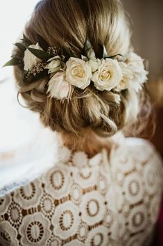 a woman with flowers in her hair is wearing a white lace top and flowered hair comb