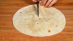 a person cutting up a tortilla on top of a wooden table