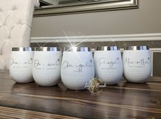 five white wine glasses with the names of bride and groom on them sitting on a wooden table