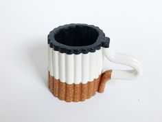 a white and black coffee cup sitting on top of a wooden handle with brown stripes