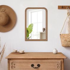 a wooden dresser sitting next to a wall with a mirror on it's side