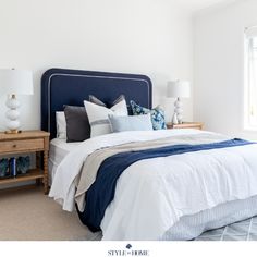 a bedroom with white walls and blue headboard, two nightstands, and a large bed