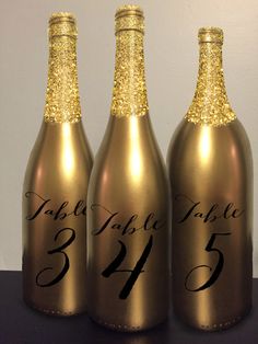 three wine bottles with gold glitter on them are labeled for the table number twenty five