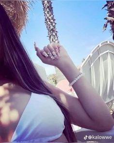 a woman with long dark hair holding onto a palm tree