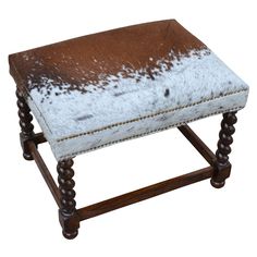 a brown and white cowhide bench with wooden legs