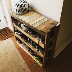 a wooden shoe rack with several pairs of shoes and a helmet on top of it