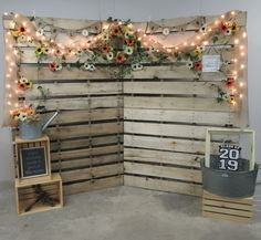 a room with wooden pallets and lights on the wall, decorated with fake flowers