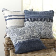 three pillows sitting on top of a wicker chair