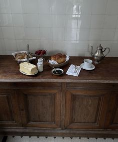 a wooden table topped with cakes and other food on top of it next to a silver teapot