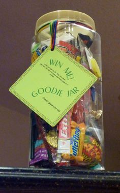 a jar filled with candies and candy sitting on top of a counter next to a sign