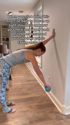 a woman is leaning against the wall with her leg up and holding a blue ball