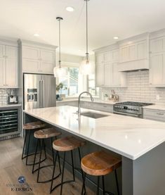 a kitchen island with stools in front of it next to an oven and refrigerator