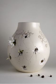 a white vase sitting on top of a table next to some dried up leaves and flowers