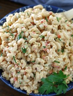 a blue bowl filled with macaroni salad and garnished with parsley