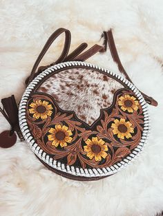 "Custom branded Cowhide Tooled Leather Round Crossbody purse with white whipstitch and yellow tooled daisies  These gorgeous round crossbody purses are made of genuine leather, pebble leather or distressed/waxed leather back and strap, tooled leather details on front and cow/goat hide Bag measures approx 10\" diameter and a 30\" purse drop fully expanded, adjustable to smaller size, we add your custom initials or farm/cow brand,  Please place in notes 2 letters for branding or \"custom messaged\ Branded Cowhide, Ranch Cowgirl, Western Bag, Circle Purse, Leather Tooling Patterns, Tooling Patterns, Round Purse