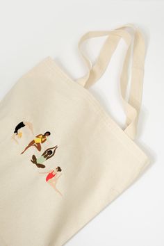 an embroidered tote bag with three women on the front and one woman behind it