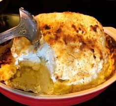 a close up of a casserole in a red dish with a spatula