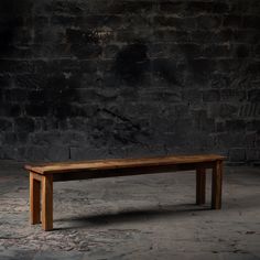 a wooden bench sitting in front of a brick wall with no one on the ground