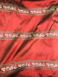 an old red cloth with white and gold designs on the edges is laying on its side