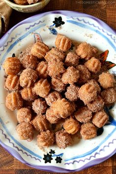 powdered sugar coated donuts on a plate next to a bowl of other doughnuts